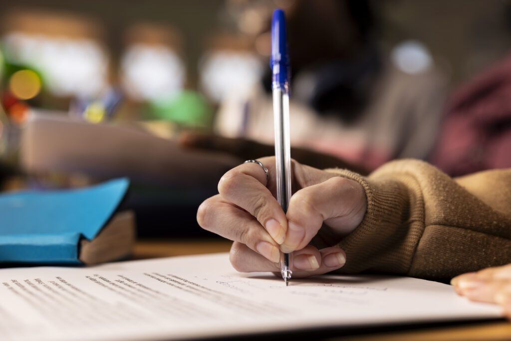 Student writing an A/L Chemistry past paper during exam practice session.
